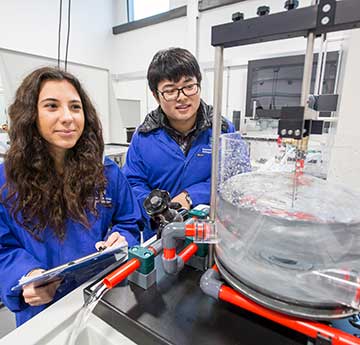 A male and female student wearing blue personal protective equipment. 