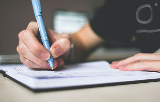 A person using a pen to write on paper