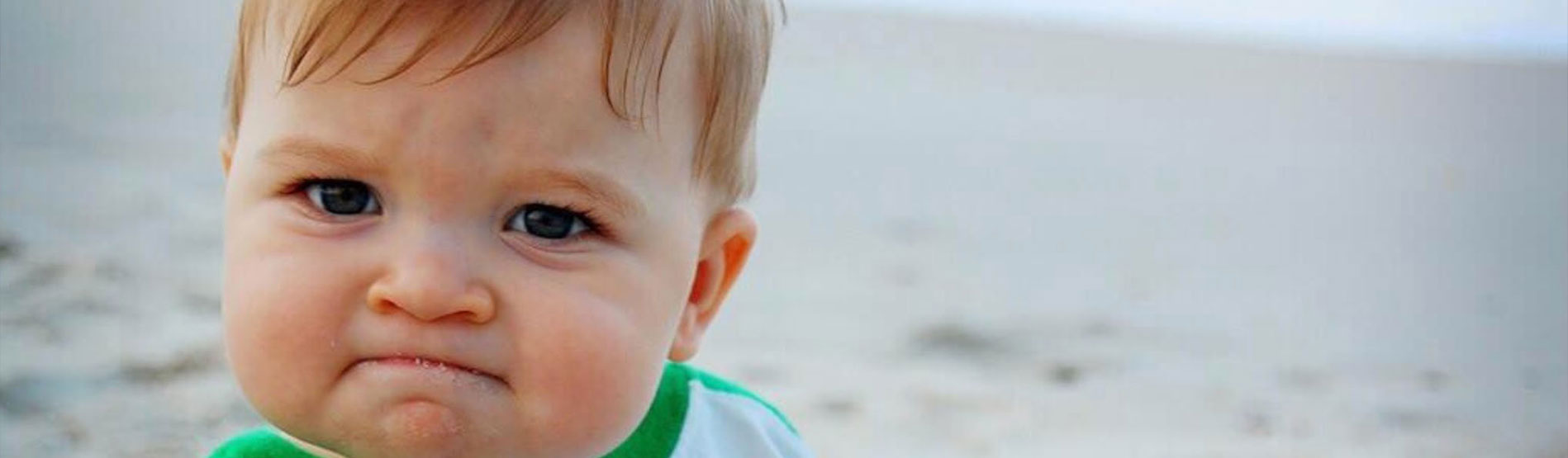 A popular meme showing a baby triumphantly holding a fistful of sand on the beach.