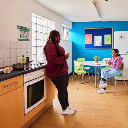 An image of two students talking to each other in a kitchen in student accommodation.