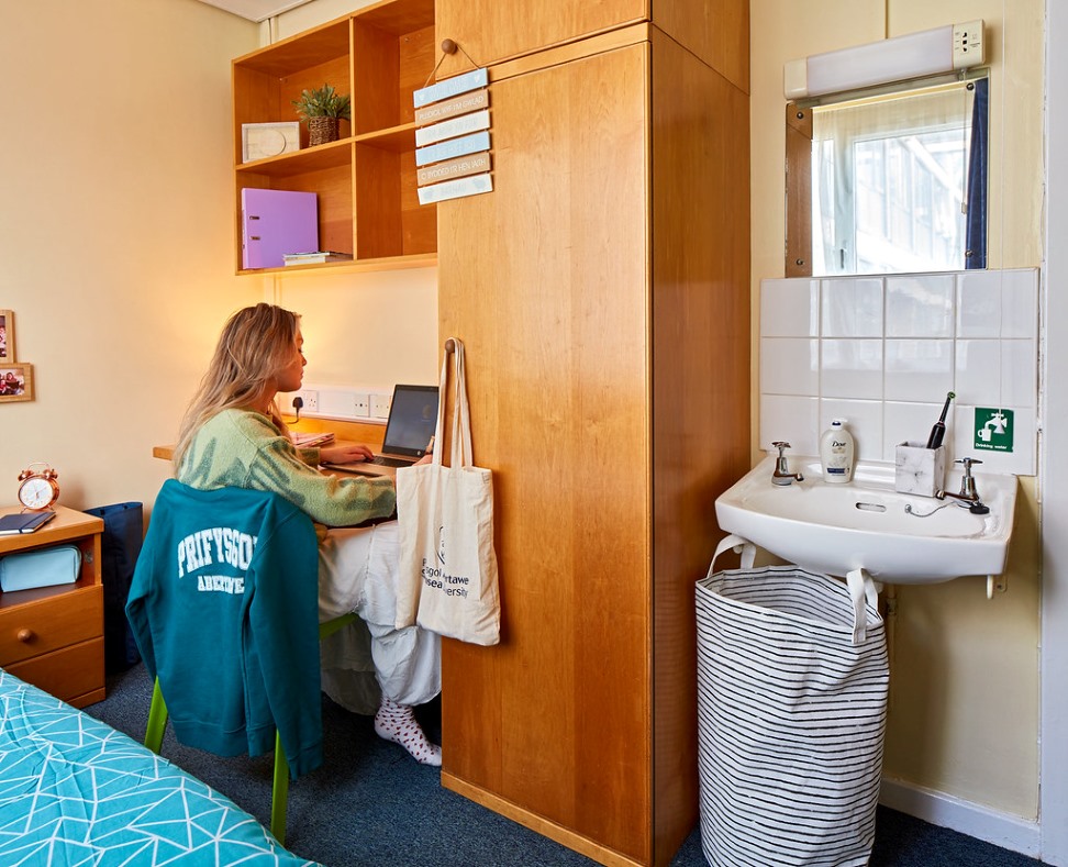 A university bedroom with a student at a desk