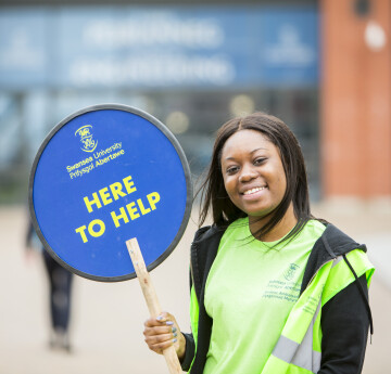 A student holding a here to help sign