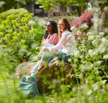 Two students sat on a bench in the University gardens