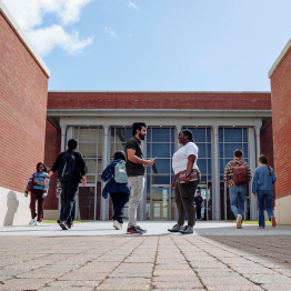 An image of students talking outside the Bay Campus library entrance.
