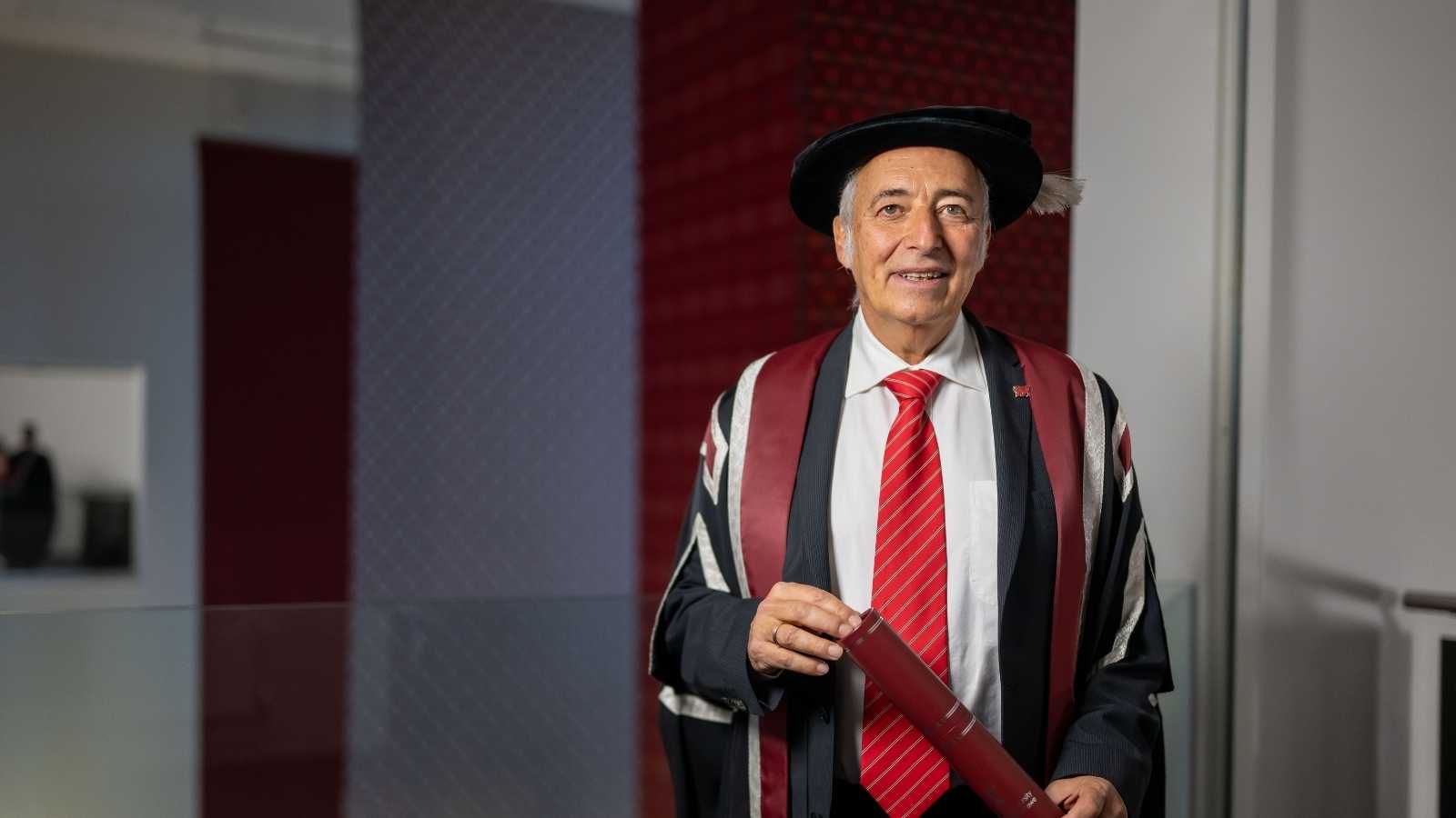 Man wearing cap & gown smiling at the camera