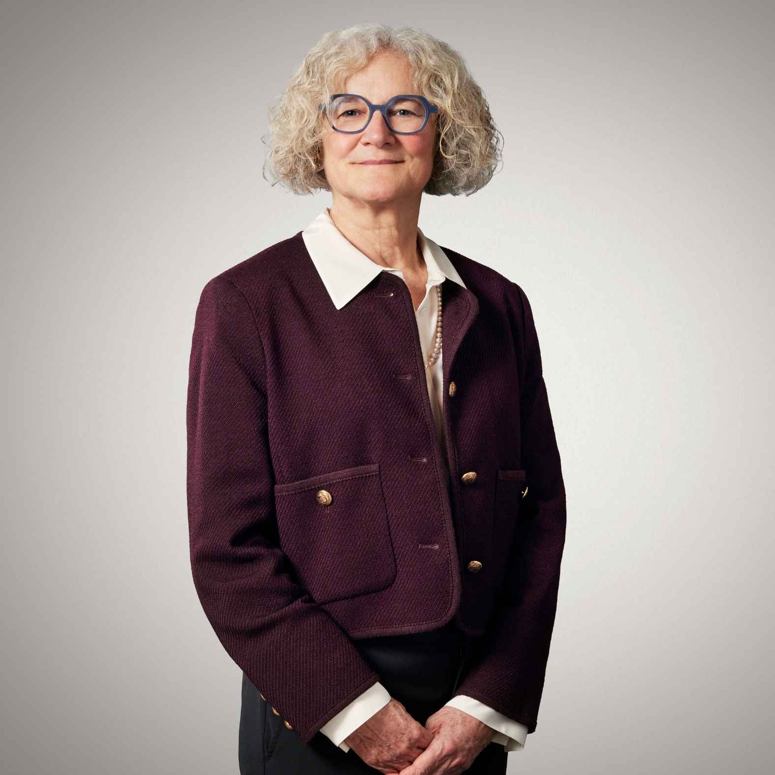 Lady wearing a burgundy suit smiling at the camera