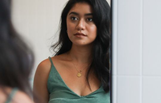 Girl looking in bathroom mirror