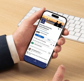 Photo of a hand holding a phone, looking at linkedin