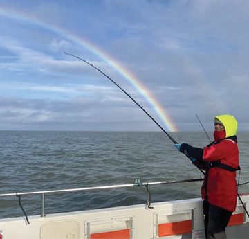 A woman on a boat at sea with a large fishing rod