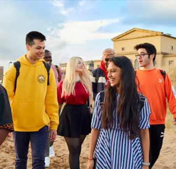 Students walking towards the beach with the Great Hall bhind them