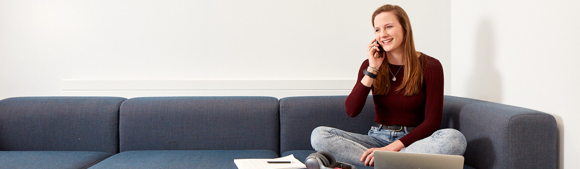 A woman on her phone sitting on a blue sofa