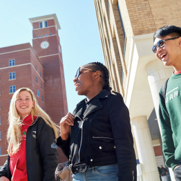 An image of three students walking through Bay Campus past the Clock Tower building.