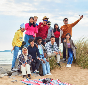 An image of a group of students taking a selfie on the beach.