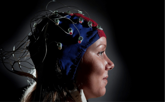 Person mewn cap penglog gydag electrodau.