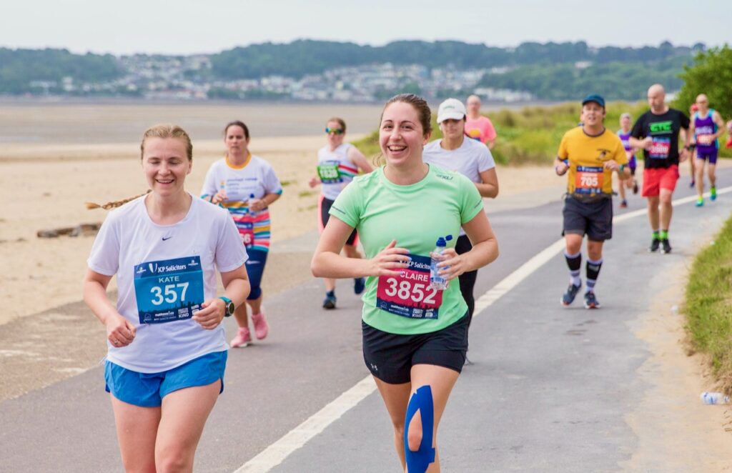 Delwedd o redwyr yn cymryd rhan yn Hanner Marathon Abertawe.