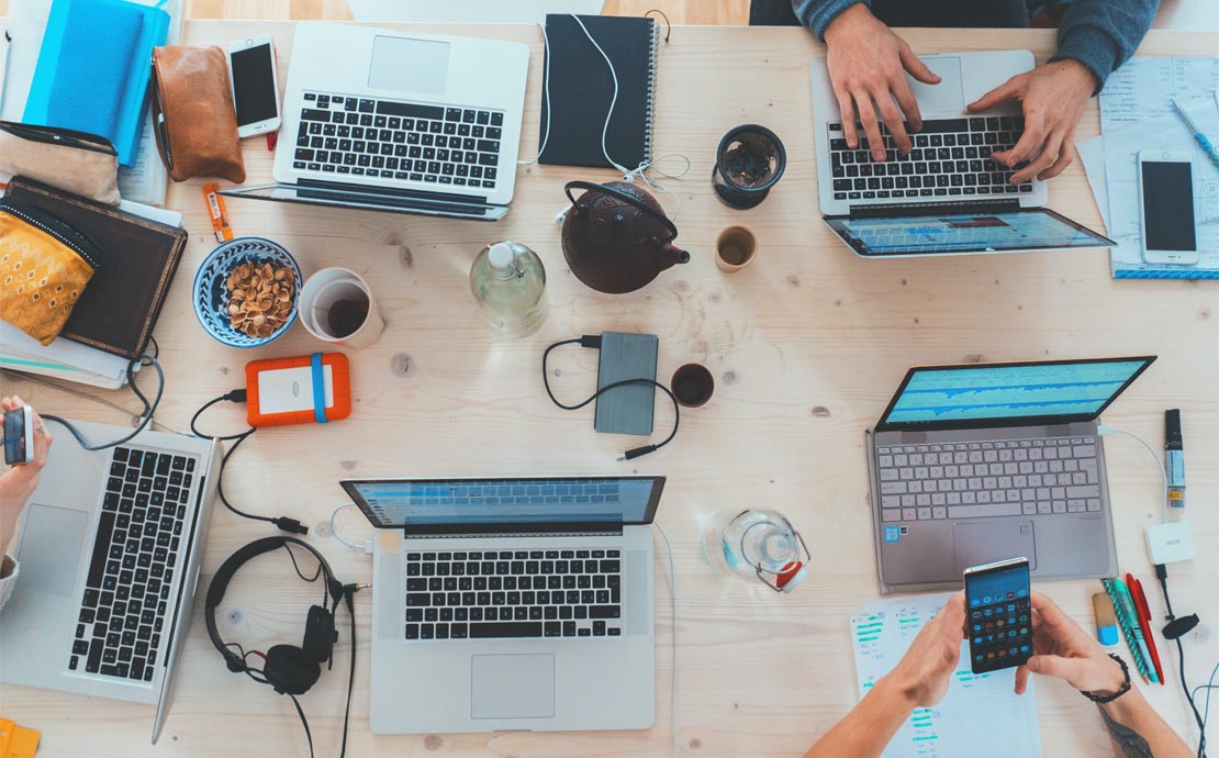 Image of a desk full of laptops and headphones 