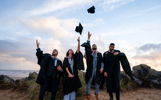 Myfyrwyr yn taflu eu capiau graddio