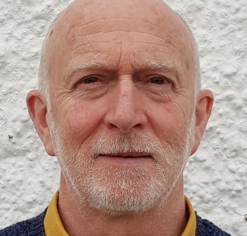 Dyn yn edrych i'r camera ac yn gwenu