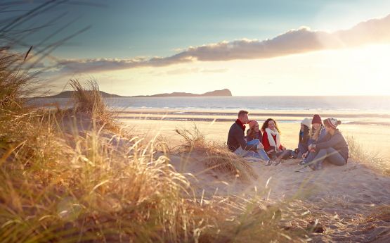 Myfyrwyr yn eistedd ar y traeth