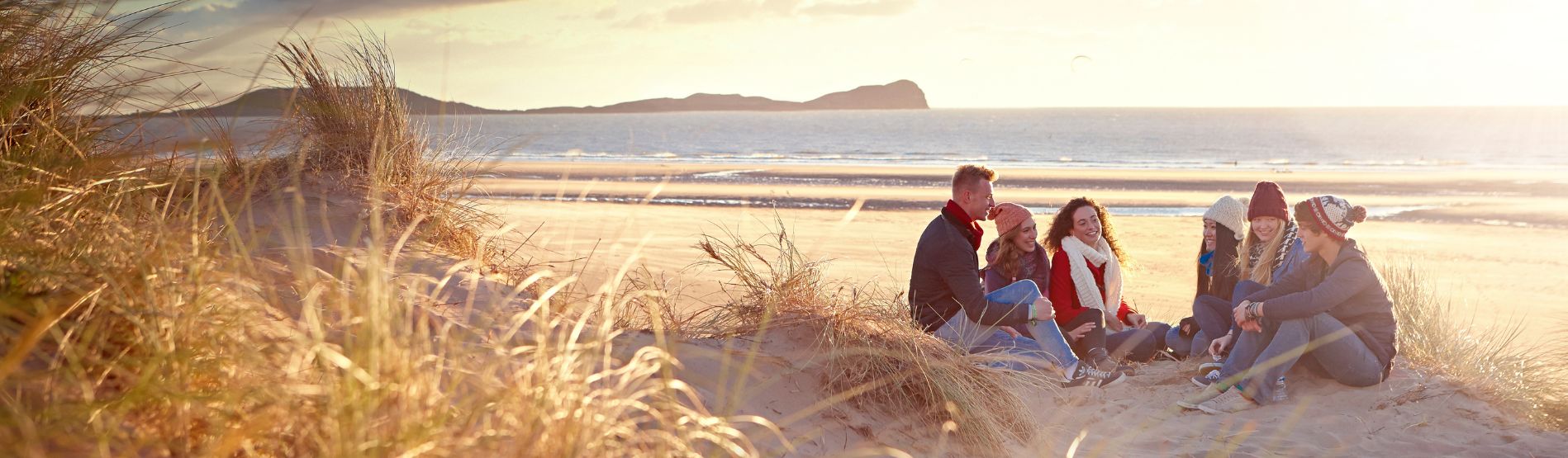 Myfyrwyr yn eisted ar y traeth 