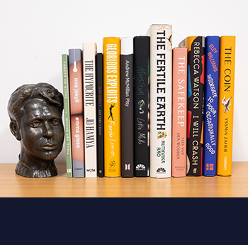 Image of bookshelf with the 12 shortlisted books and bust of Dylan Thomas