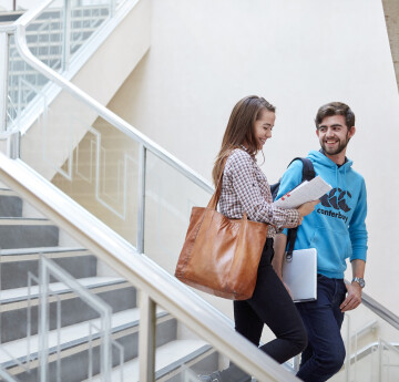 Two students walking down a set of stairs