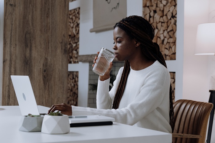 woman sitting at laptop drinking water