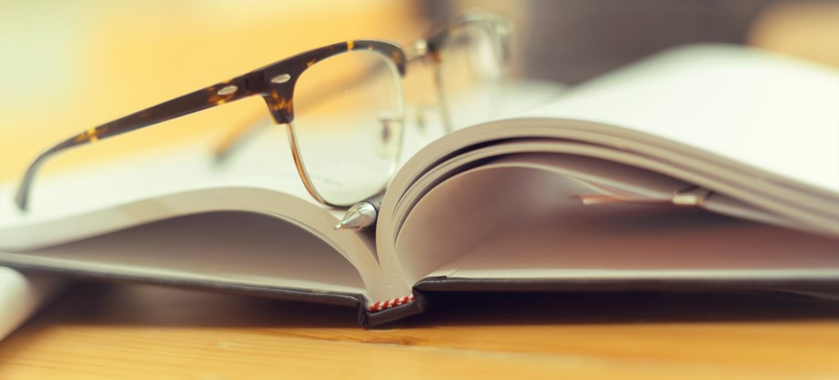 A pair of glasses resting on an open book.
