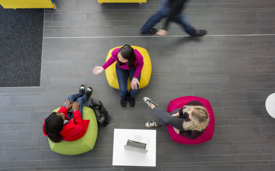 A birds-eye view of three people talking while sitting on beanbags.