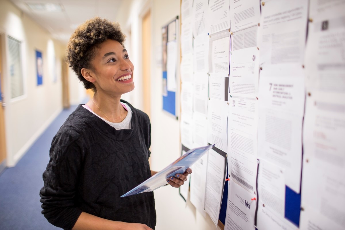 Female student smiling and looking at noticeboard