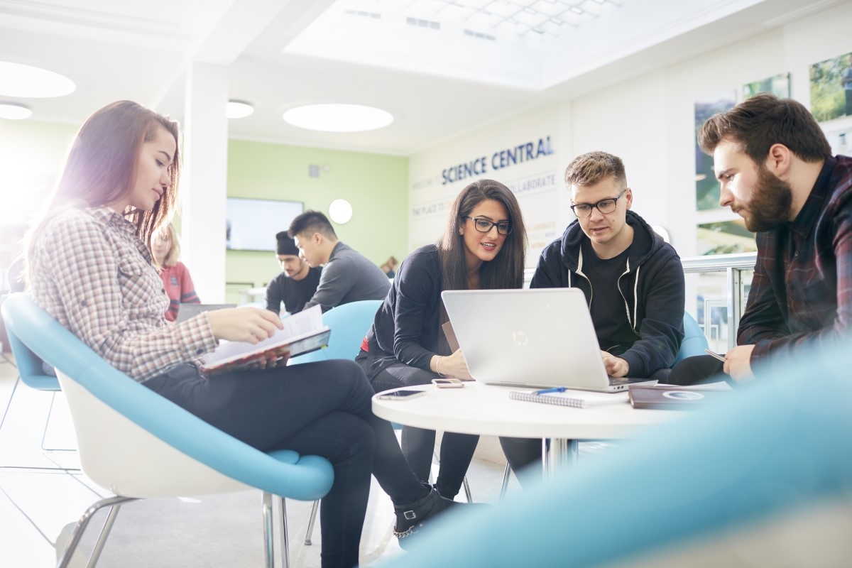 Group of students sitting around a laptop and working.