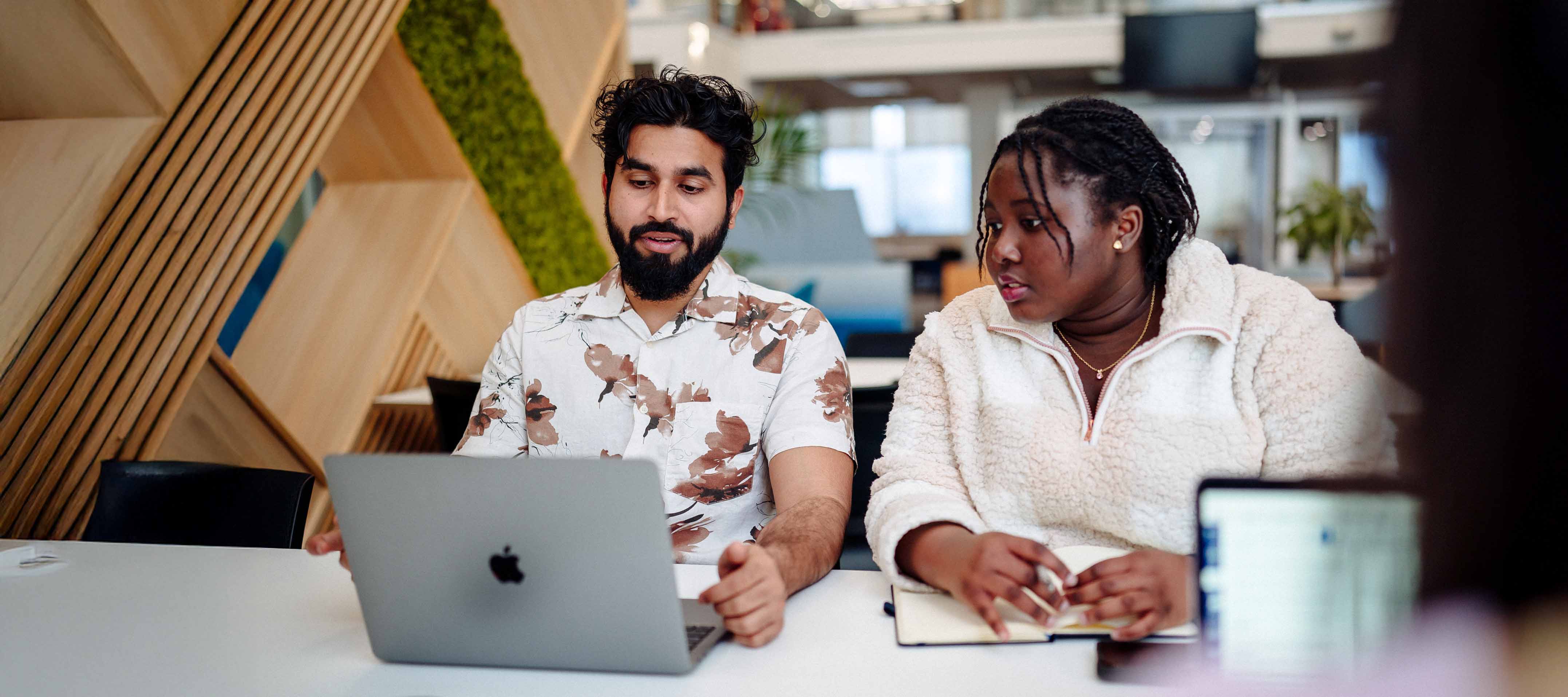 dwy ferch yn gwenu wrth gerdded drwy'r Campws