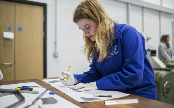 Student writing on paper in lab coat