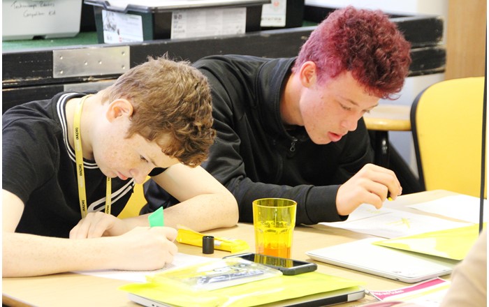 Dau ddisgybl yn gweithio mewn digwyddiad Technocamps, cyn Covid-19: bydd gweithlyfrau newydd yn galluogi disgyblion heb fynediad at y rhyngrwyd i astudio pynciau STEM hyd yn oed os bydd ysgolion ar gau.