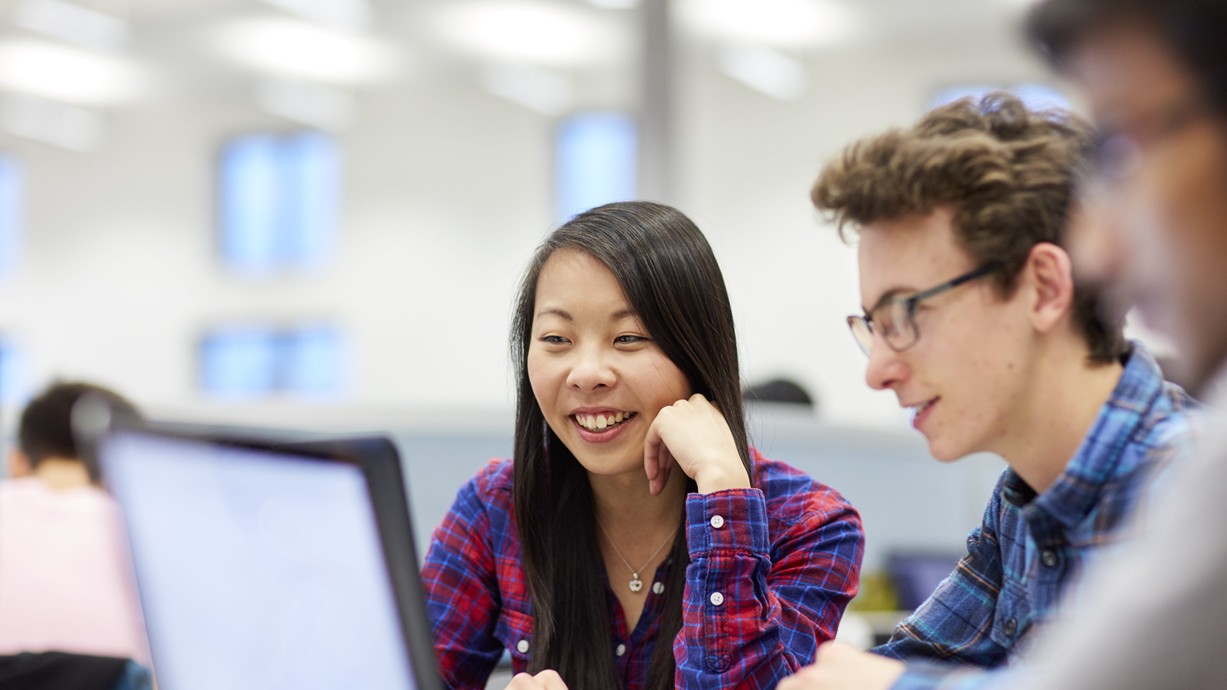 Grŵp o fyfyrwyr yn gweithio gan ddefnyddio gliniaduron.