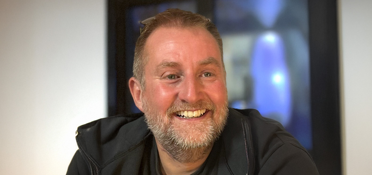 Pen a hombiau dyn gwalltog yn gwenu