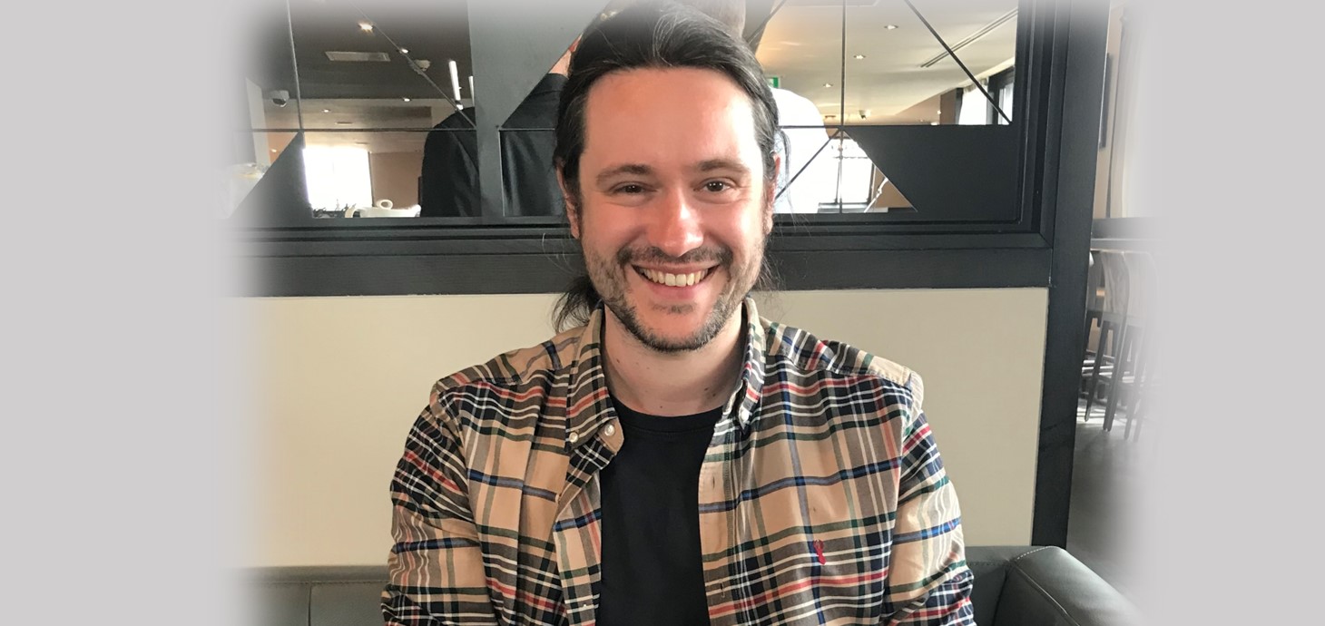 Dyn yn gwenu yn eistedd oddi mewn