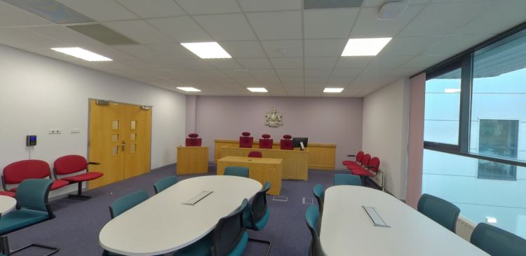 Ystafell llys gyda mainc barnwr, seddi a byrddau cynadledda