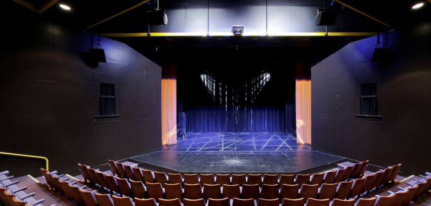 Theatr wag gyda llwyfan, llenni â goleuadau glas, a seddi