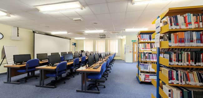 Canolfan Adnoddau Dysgu gyda chyfrifiaduron, desgiau astudio a silffoedd llyfrau