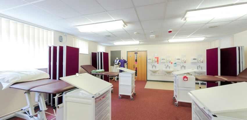 Swît hyfforddiant clinigol gyda gwelyau archwilio, sgriniau preifatrwydd a sinciau