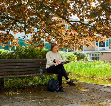 students sitting on benches outside the Vivian Pool on Singleton Park Campus