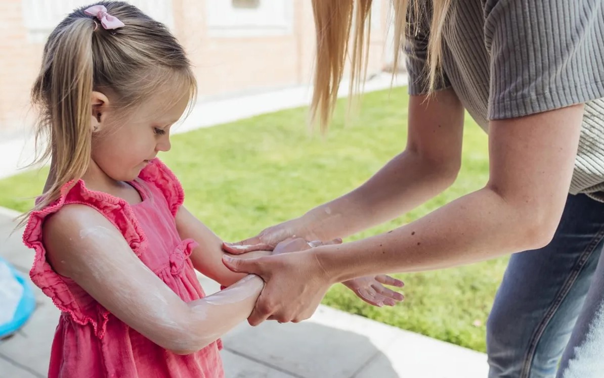 Adult applying sunscreen to child