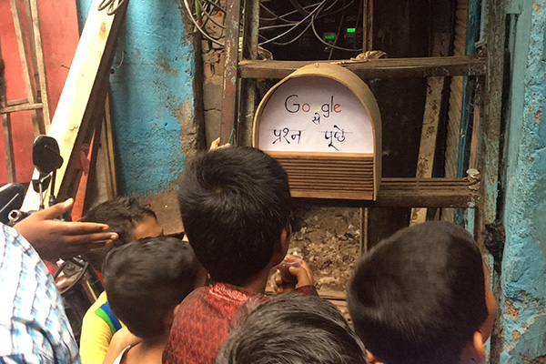 Young children surrounding a google speaker