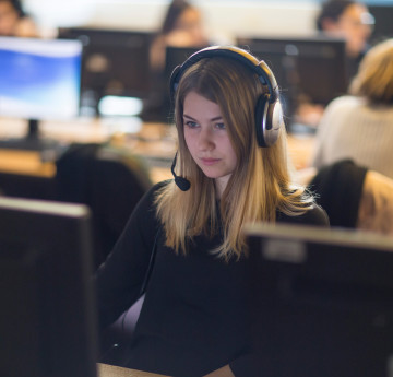 Woman with head set on looking at a computer