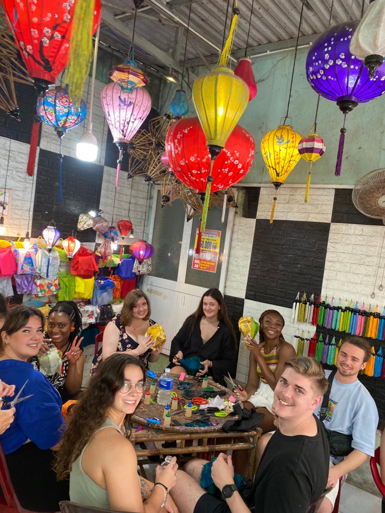 Students sitting around a table with colorful lanterns on ceiling