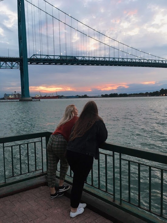 student standing overlooking water and bridge