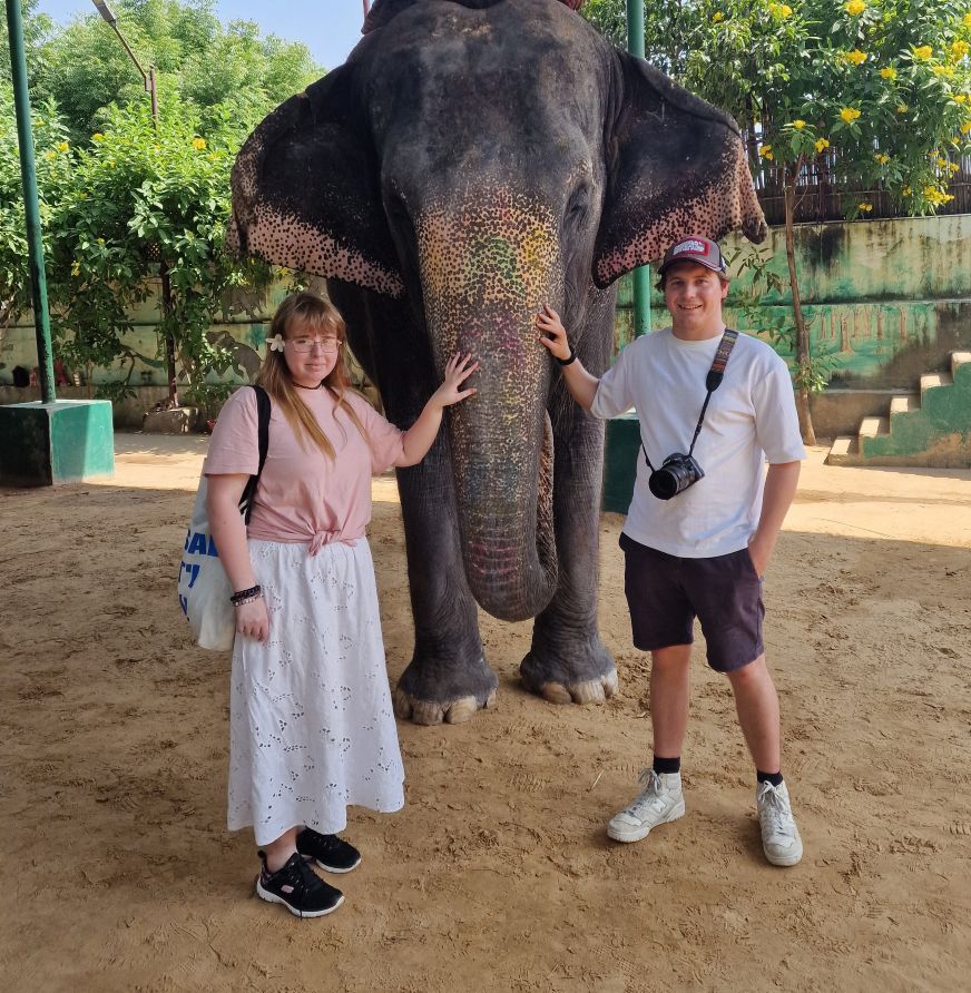 Two students standing with elephant.