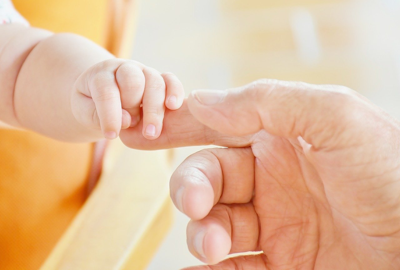 baby and parent holding hands