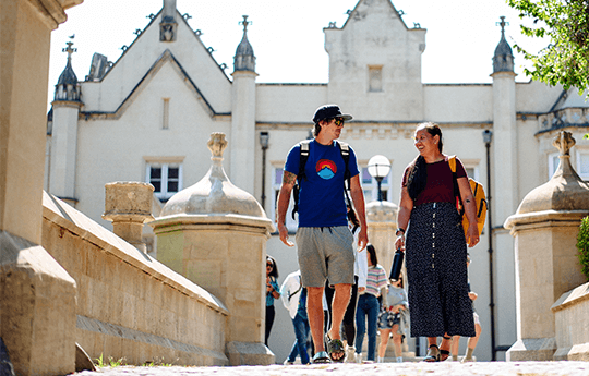 A group of students walking across Singleton Park Campus, with Singleton Abbey in the background.